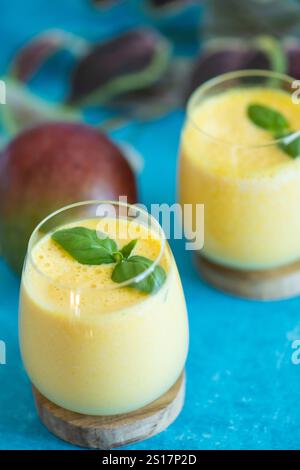 Freschi lassi di mango in bicchieri su sfondo blu con spazio per le copie. Indiano sana detossica ayurvedica bevanda fredda con mango. Lassi di freschezza a base di yogur Foto Stock