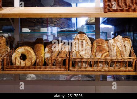 Pani di pane italiano appena sfornati su scaffali di legno in una panetteria. Foto Stock