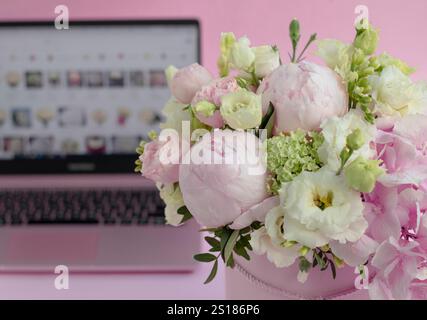 bouquet di fiori in una scatola da primo piano, sullo sfondo di un laptop aperto Foto Stock