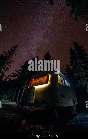 Rimorchio da viaggio in camper d'epoca sotto lo splendido cielo notturno Campeggio nelle Montagne Rocciose canadesi Foto Stock