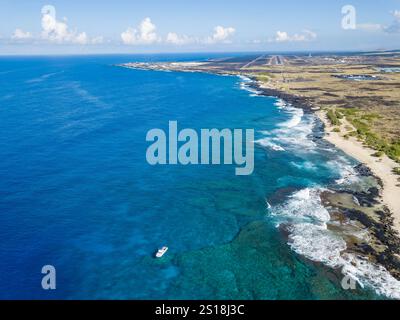 Una vista aerea di una barca ancorata al largo di Kohanaiki Beach con Kalihi Point e l'Aeroporto Internazionale di Kona Keahole (KOA) sullo sfondo, Kona, Hawa Foto Stock