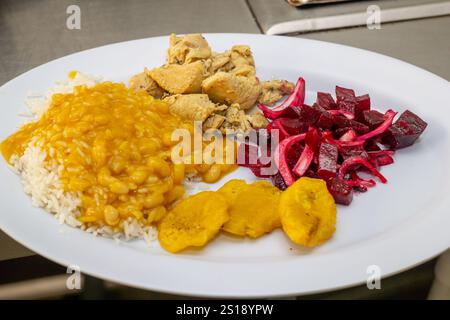 cuocere servendo habichuelas in un tipico piatto dominicano, cuocere riso, pollo, insalata, riso bianco, pasto gustoso Foto Stock