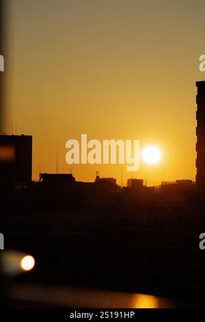 Il sole mattutino appare basso sul cielo dell'alba dorato senza nuvole. La sua luce scintillante si riflette delicatamente sulla ringhiera di un alto balcone. Foto Stock