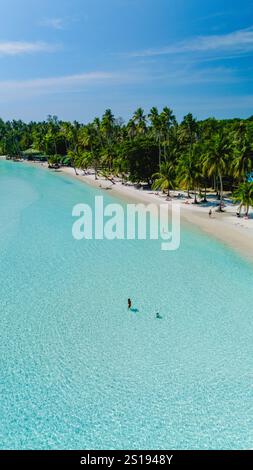 Le morbide onde turchesi si infrangono su sabbie bianche incontaminate a Koh Kood, Thailandia. La luce del sole balla sull'acqua mentre i visitatori apprezzano la bellezza tranquilla di questo paradiso tropicale, circondato da una vegetazione lussureggiante. Foto Stock