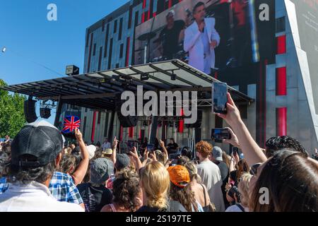 I fan tifosi si con entusiasmo mentre Robbie Williams sale sul palco per uno spettacolo pomeridiano a Melbourne, Australia. Robbie Williams, Rock Star, ha affascinato 8.000 fan alla Federation Square di Melbourne, riempiendo il locale fino alla sua massima capacità per un concerto gratuito che celebra il suo film Better Man. La soleggiata esibizione pomeridiana ha visto la folla cantare, ballare e applaudire mentre Robbie mostrava i suoi successi iconici. I fan hanno portato cartelli e sorrisi, creando un'atmosfera vivace e gioiosa. Questo evento indimenticabile ha sottolineato il legame di Robbie con il suo pubblico e la passione per la musica di Melbourne. Foto Stock