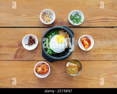 Bibimbap, una ciotola di riso coreano ripiena di verdure assortite, salsa gochujang, ricoperta di uova fritte, servita con contorni Foto Stock