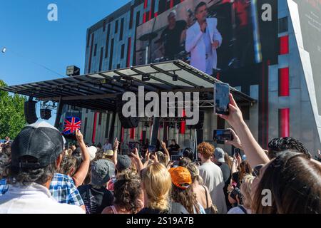 I fan tifosi si con entusiasmo mentre Robbie Williams sale sul palco per uno spettacolo pomeridiano a Melbourne, Australia. Robbie Williams, Rock Star, ha affascinato 8.000 fan alla Federation Square di Melbourne, riempiendo il locale fino alla sua massima capacità per un concerto gratuito che celebra il suo film Better Man. La soleggiata esibizione pomeridiana ha visto la folla cantare, ballare e applaudire mentre Robbie mostrava i suoi successi iconici. I fan hanno portato cartelli e sorrisi, creando un'atmosfera vivace e gioiosa. Questo evento indimenticabile ha sottolineato il legame di Robbie con il suo pubblico e la passione per la musica di Melbourne. (Foto di Foto Stock