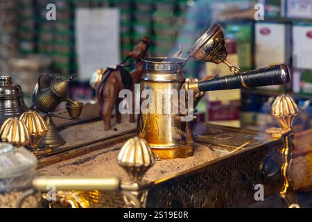 Caffè arabo estratto in una dallah (caffettiera araba) su sabbia calda Foto Stock