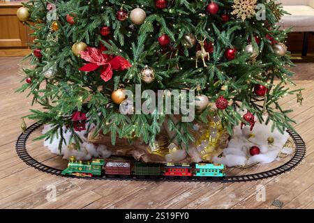 Un albero di Natale festivo splendidamente decorato con un affascinante treno posizionato sotto Foto Stock