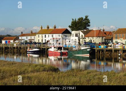 Southwold, Suffolk, Inghilterra, Regno Unito - le barche si riflettono sul fiume Blyth nel Southwold Harbour accanto all'Harbour Inn e a vari cottage e aziende Foto Stock