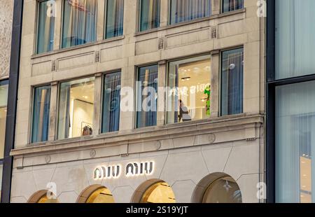 una donna che lavora in una finestra al secondo piano sulla 57esima strada est, new york Foto Stock