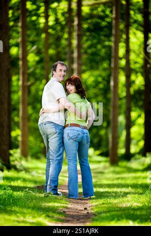 La vita inizia a 40 anni. Una coppia matura che si diverte insieme mentre si godono il caldo clima estivo in un parco alberato soleggiato. Foto Stock