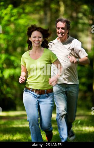 La vita inizia a 40 anni. Una coppia matura spensierata che si gode un momento di giovinezza in un bosco soleggiato. Foto Stock