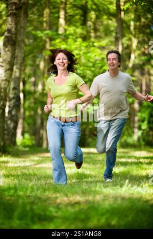 La vita inizia a 40 anni. Una coppia matura spensierata che si gode un momento di giovinezza in un bosco soleggiato. Foto Stock