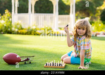 Bambini da sogno e concetto d'infanzia. Il ragazzo mostra i pezzi degli scacchi su una scacchiera. Un bambino intelligente concentrato e pensante che gioca a scacchi. Foto Stock