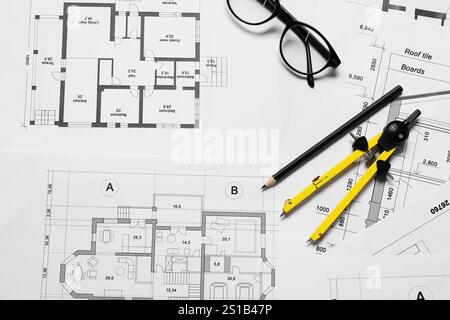 Diversi disegni architettonici, matita, occhiali e divisore sul tavolo, disposizione piatta Foto Stock