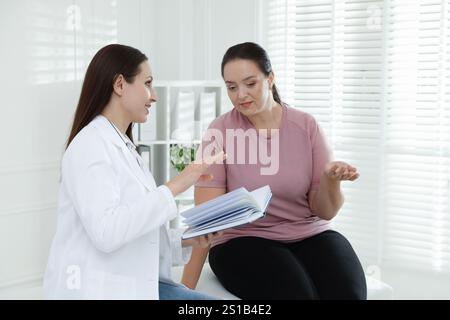 Nutrizionista con notebook che fornisce consigli alle donne in sovrappeso in ospedale Foto Stock