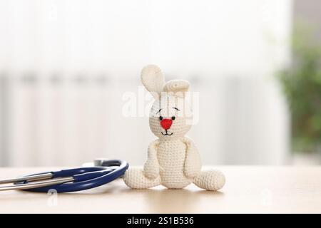 Concetto pediatrico. Coniglietto giocattolo con stetoscopio sul tavolo all'interno Foto Stock