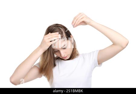 Problema di perdita dei capelli. Ragazza che applica il siero sulla linea di capelli su sfondo bianco Foto Stock