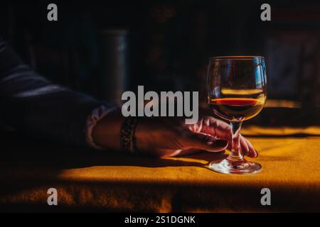 Donna che tiene un bicchiere di vino rosso alla luce del sole Foto Stock