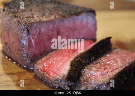 Bistecca succosa di media rara con crosta scottata su un asse di legno Foto Stock