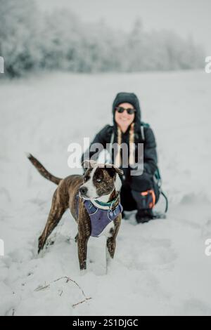 una donna che posa con il cane mentre cammina nella neve, maine. Foto Stock