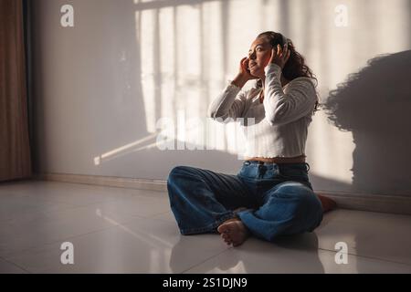 Donna che ascolta musica con le cuffie a casa Foto Stock