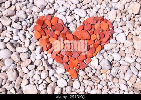 Forma a cuore rosso fatta di pietre e ciottoli da spiaggia. San Valentino simbolo. Foto Stock