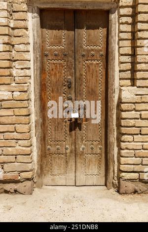 Una porta in legno splendidamente lavorata con tradizionali incisioni si erge chiusa a chiave a Bukhara, Uzbekistan, che mostra un ricco patrimonio architettonico. Foto Stock