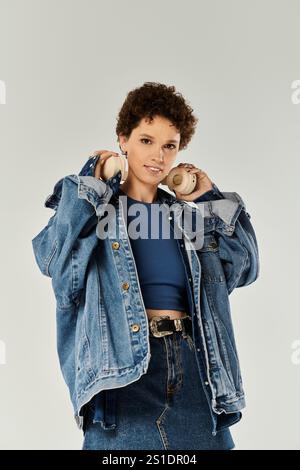 Una giovane donna casual ed elegante posa in studio, indossando una giacca in denim e dando prova di fiducia. Foto Stock
