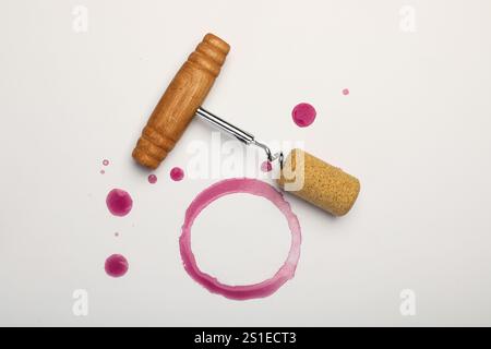 Cavatappi, sughero e macchie di vino rosso su sfondo bianco, vista dall'alto Foto Stock