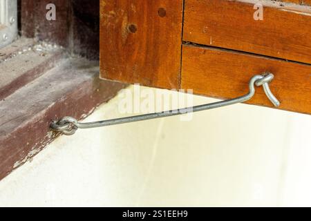 "Finestre in legno robuste fissate saldamente con robusti ganci in metallo, combinando un fascino rustico con un tocco di funzionalità industriale perfetto per classi Foto Stock
