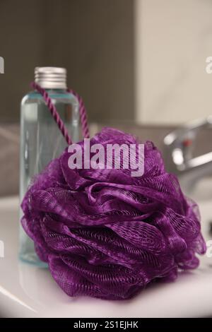 Soffione viola per doccia e bottiglia di gel per il corpo sul lavandino in bagno, primo piano Foto Stock