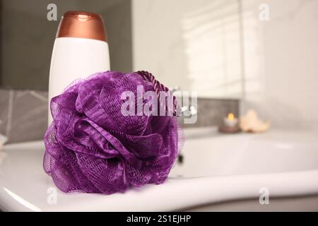 Soffio doccia viola e bottiglia di gel per il lavaggio del corpo sul lavandino in bagno, spazio per il testo Foto Stock