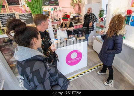 Piccola caffetteria e pasticceria The Cake Bench nella cittadina di mercato di Suffolk, Framlingham, con personale e clienti che bevono vino bianco per celebrare l'evento. Foto Stock
