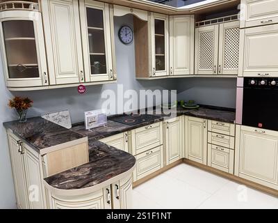 Kiev, Ucraina - 3 gennaio 2025: Elegante design della cucina con armadi color crema, ripiani in stile marmo ed elettrodomestici incorporati. Funzione Foto Stock