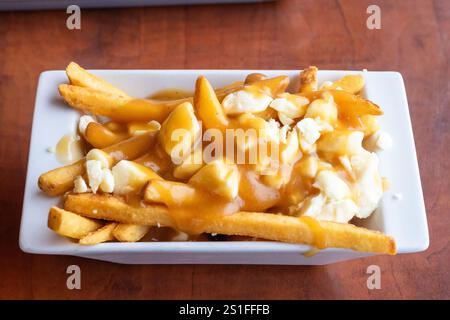 Piatto di poutine con patatine croccanti condite con cagliate di formaggio e ricco sugo di carne bruno in un ristorante locale di Alberta, Canada Foto Stock
