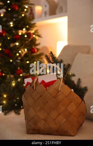 Cestino in vimini con decorazioni natalizie sul divano al coperto Foto Stock