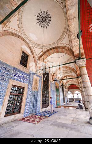 Moschea Rustem Pasha piastrelle Iznik Istanbul // ISTANBUL, Turchia — il chiostro d'ingresso della Moschea Rustem Pasha (conosciuta anche come Rüstem Paşa Camii) mostra la famosa piastrella blu e bianca di Iznik lungo le sue pareti. Completata intorno al 1563 dal maestro architetto Mimar Sinan, la moschea presenta circa 2.300 piastrelle Iznik individuali disposte in oltre 80 modelli distinti, che rappresentano uno degli usi più estesi della decorazione in ceramica nell'architettura religiosa ottomana. Commissionata dal Gran Visir Rüstem Pasha e completata dopo la sua morte nel 1561, la moschea è ampiamente considerata una Foto Stock