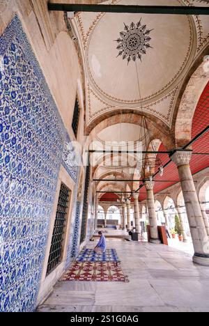 Moschea Rustem Pasha piastrelle Iznik Istanbul // ISTANBUL, Turchia — il chiostro d'ingresso della Moschea Rustem Pasha (conosciuta anche come Rüstem Paşa Camii) mostra la famosa piastrella blu e bianca di Iznik lungo le sue pareti. Completata intorno al 1563 dal maestro architetto Mimar Sinan, la moschea presenta circa 2.300 piastrelle Iznik individuali disposte in oltre 80 modelli distinti, che rappresentano uno degli usi più estesi della decorazione in ceramica nell'architettura religiosa ottomana. Commissionata dal Gran Visir Rüstem Pasha e completata dopo la sua morte nel 1561, la moschea è ampiamente considerata una Foto Stock