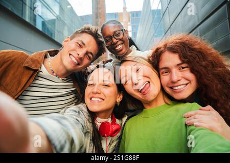 Un gruppo di giovani amici che sorridono e fanno un selfie insieme, mostrando gioia e felicità. Cinque studenti adolescenti multirazziali che si divertono a fare un ritratto, ridendo guardando la macchina fotografica. Foto di alta qualità Foto Stock