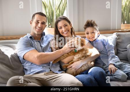 Allegri genitori giovani e simpatico figlio che tiene in mano un gatto arancione Foto Stock