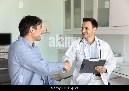 Medico felice e paziente che stringono la mano in ufficio ospedaliero Foto Stock