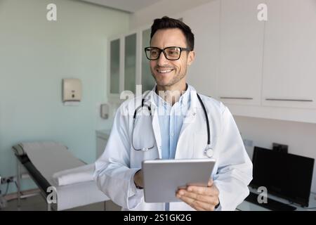 Allegro giovane medico professionista in occhiali utilizzando tablet Foto Stock
