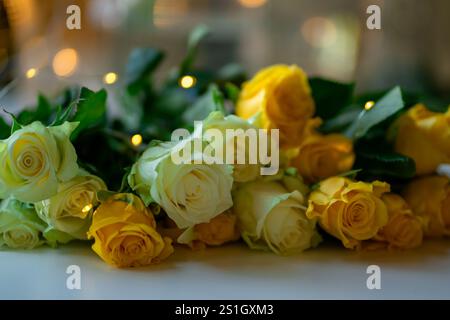 Un bouquet di rose bianche e gialle gialle giace sul tavolo Foto Stock