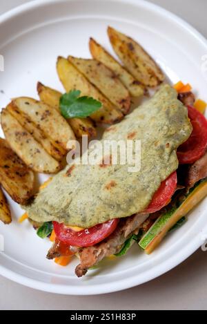 Spicchi di patate al forno e tortilla con pollo arrosto e vegetale serviti in un piatto. Foto Stock