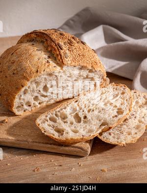 Pane integrale appena sfornato su un tagliere di legno con fette disposte accanto ad esso Foto Stock