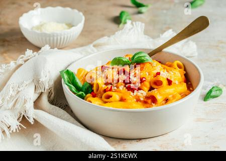 Rigatoni italiani con salsa cremosa di zucca, cipolle di primavera fresche e parmigiano, ciotola di spaghetti di zucca Foto Stock