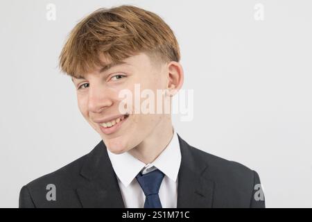 Felice ragazzo di sedici anni che indossa un completo, girato in studio su sfondo bianco Foto Stock