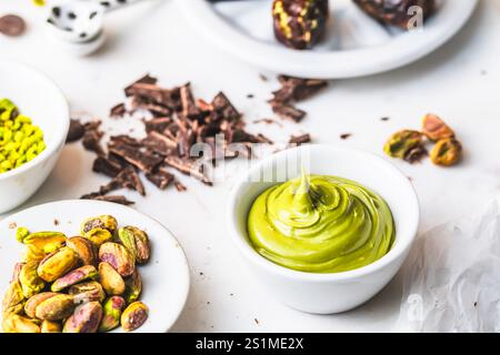 Pistacchi, crema di pistacchio, kataifi, cioccolato: Ingredienti per preparare il cioccolato Dubai alla moda su sfondo bianco Foto Stock